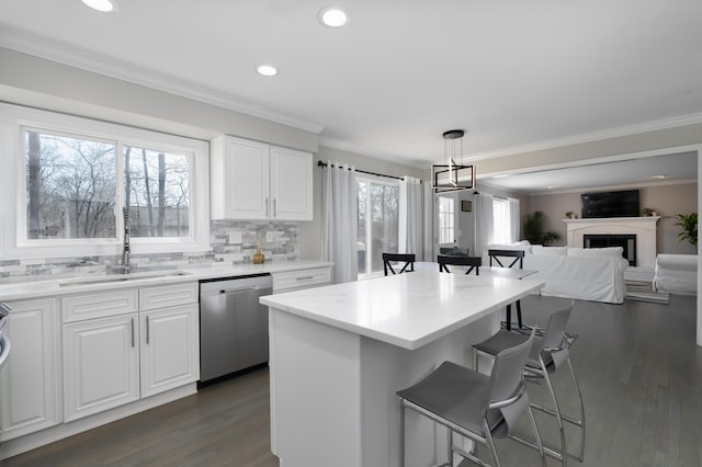 kitchen with a sink, stainless steel dishwasher, a breakfast bar area, and white cabinets