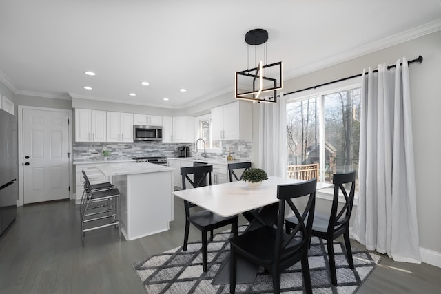 dining space featuring a wealth of natural light, an inviting chandelier, ornamental molding, and dark wood-style flooring