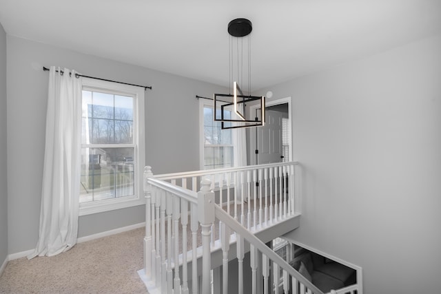 stairway with baseboards, a chandelier, and carpet flooring