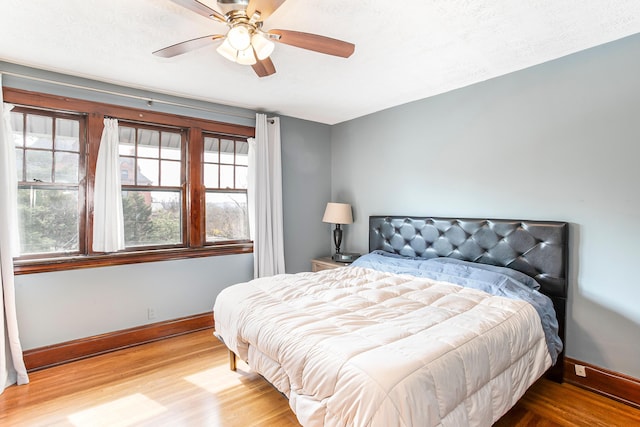 bedroom with a ceiling fan, baseboards, and wood finished floors