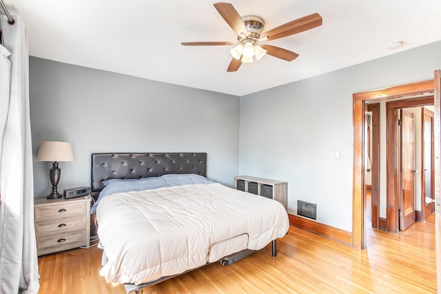 bedroom with light wood-type flooring, baseboards, visible vents, and a ceiling fan