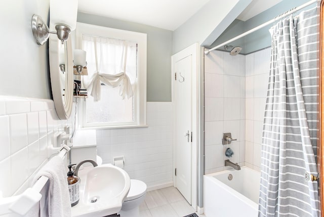 full bathroom featuring toilet, shower / bath combo, tile patterned floors, tile walls, and a sink