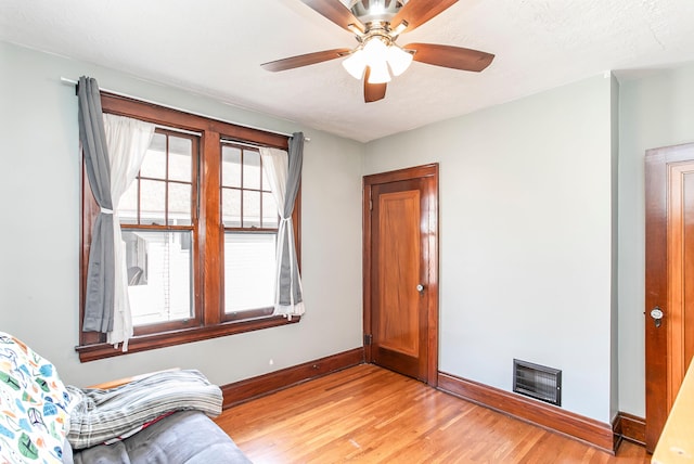 living area featuring a textured ceiling, light wood-style floors, visible vents, and baseboards