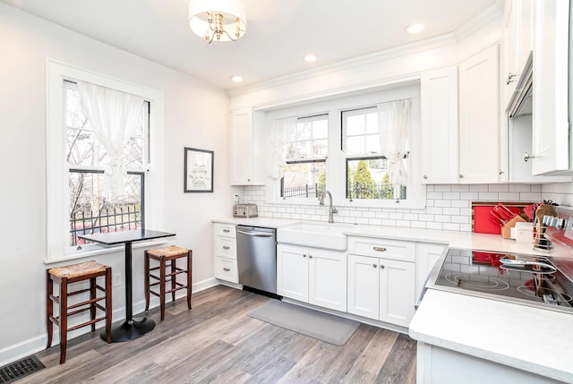 kitchen with visible vents, a sink, light wood-style floors, appliances with stainless steel finishes, and decorative backsplash