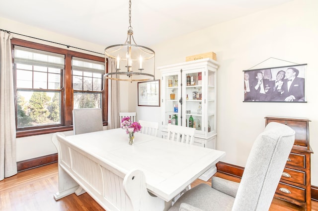 dining space featuring a notable chandelier, baseboards, and light wood-style floors