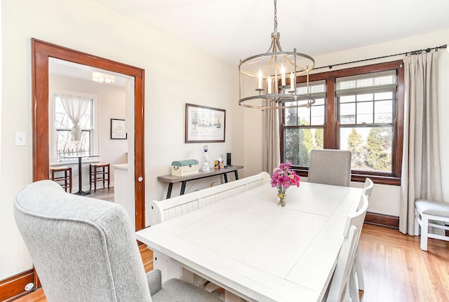 dining room featuring baseboards, a notable chandelier, and light wood-style flooring