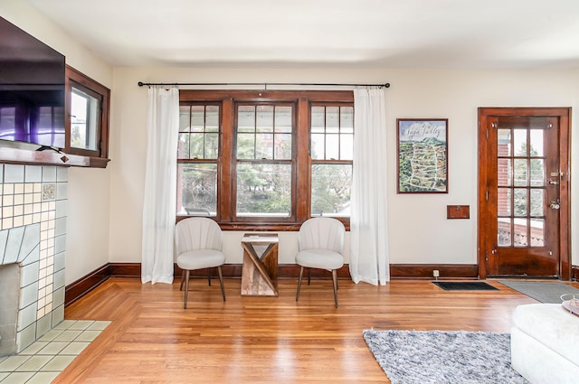 interior space with visible vents, a tile fireplace, baseboards, and wood finished floors