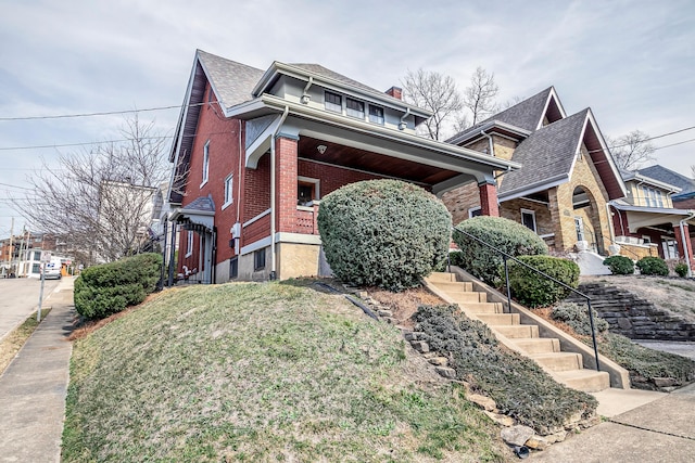 view of side of home featuring brick siding, stairs, a yard, and roof with shingles