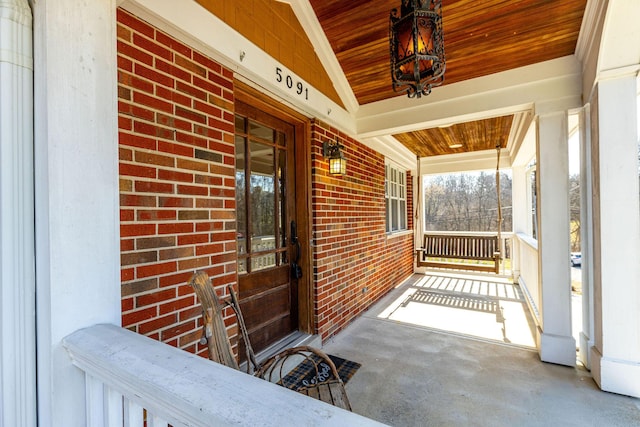 entrance to property featuring brick siding and covered porch