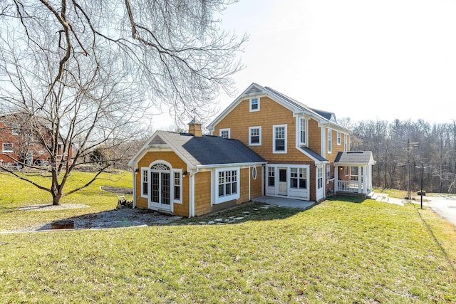 shingle-style home featuring a front yard and a chimney