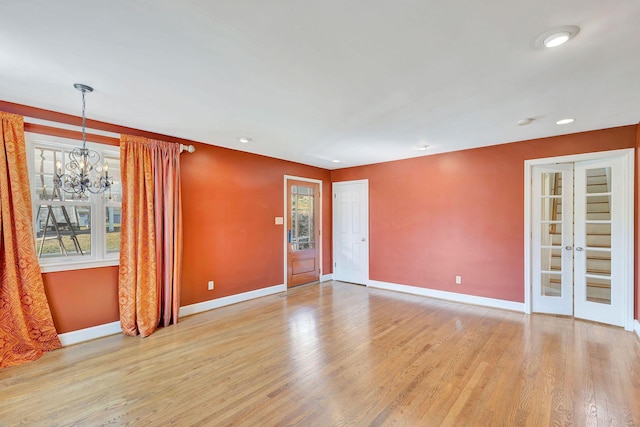 unfurnished room featuring recessed lighting, baseboards, a notable chandelier, and light wood-style flooring