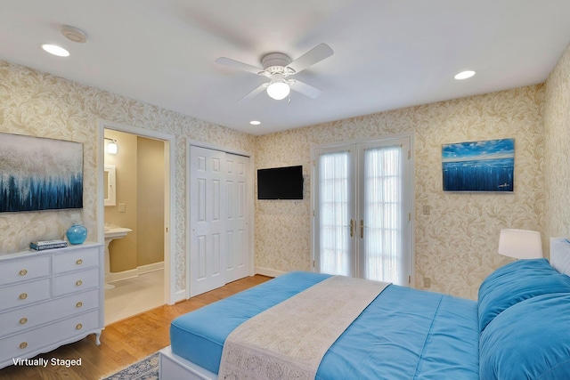 bedroom featuring wood finished floors, baseboards, wallpapered walls, ensuite bath, and french doors