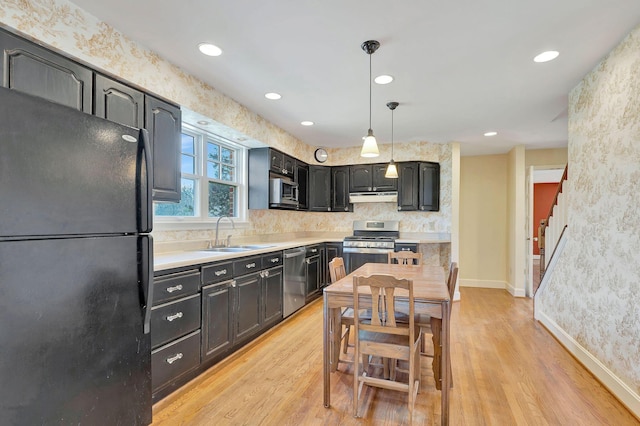 kitchen featuring a sink, light wood-style flooring, appliances with stainless steel finishes, and range hood