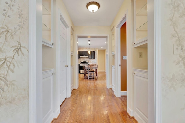 corridor featuring light wood-type flooring and baseboards