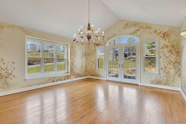 empty room with french doors, wood finished floors, vaulted ceiling, and wallpapered walls