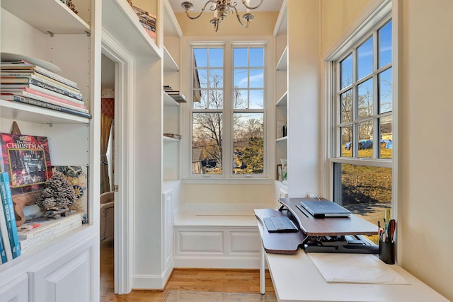 home office with light wood-style floors and a notable chandelier