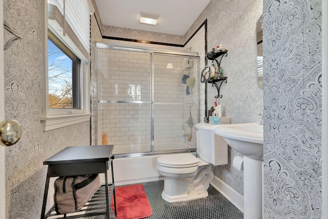 full bath featuring shower / bath combination with glass door, tile patterned flooring, and toilet