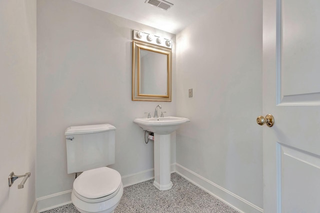 half bath featuring toilet, baseboards, visible vents, and a sink