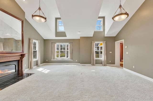 unfurnished living room featuring high vaulted ceiling, a fireplace with flush hearth, plenty of natural light, and carpet flooring