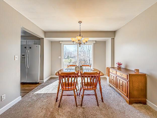 dining area featuring baseboards, carpet, and a chandelier