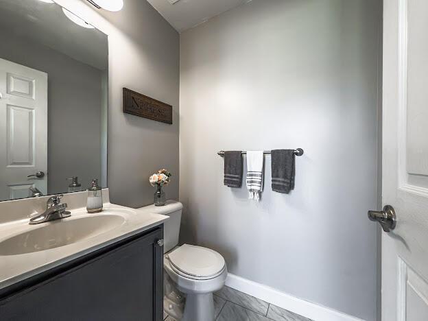 half bathroom with toilet, vanity, and baseboards