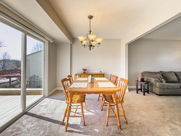 carpeted dining area featuring a notable chandelier and baseboards