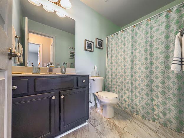 bathroom featuring a shower with shower curtain, marble finish floor, toilet, and vanity