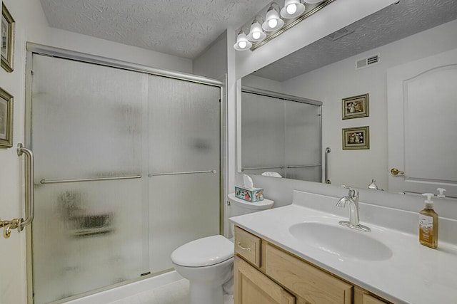 bathroom featuring visible vents, toilet, vanity, a stall shower, and a textured ceiling