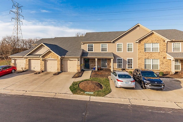 view of front of house featuring brick siding, driveway, an attached garage, and roof with shingles