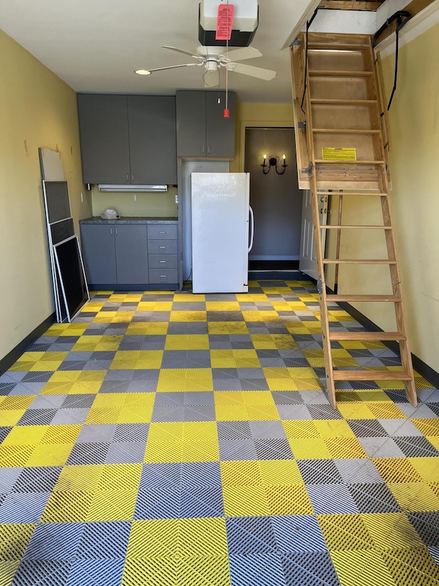 interior space with a garage door opener, baseboards, freestanding refrigerator, and ceiling fan