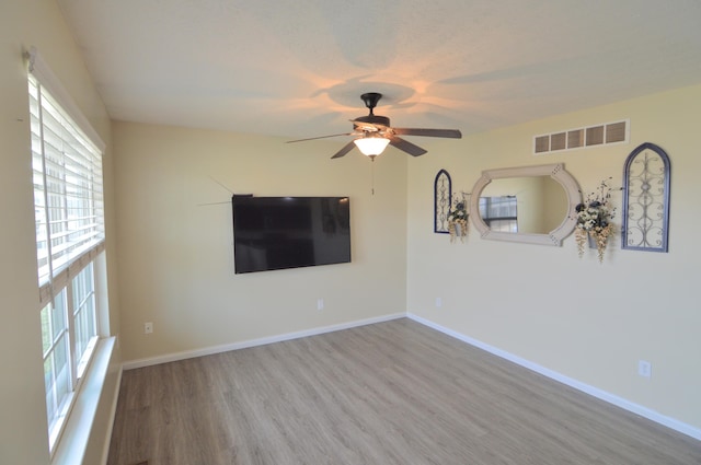 unfurnished living room with visible vents, baseboards, wood finished floors, and a ceiling fan