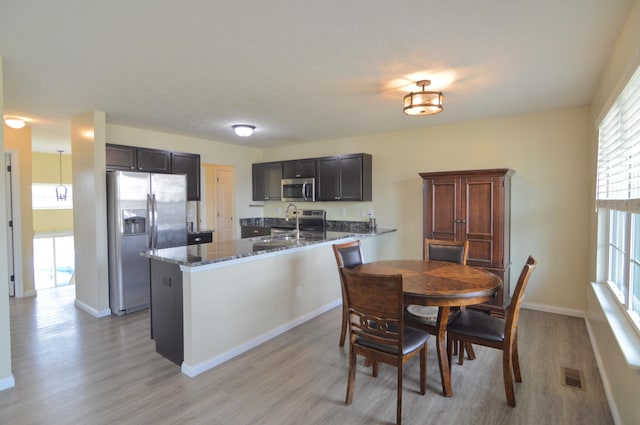 dining space featuring visible vents, light wood-style flooring, and baseboards