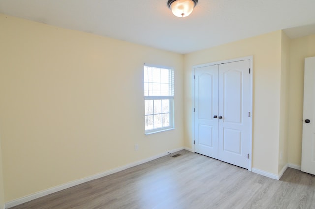 unfurnished bedroom featuring a closet, visible vents, baseboards, and light wood-style floors