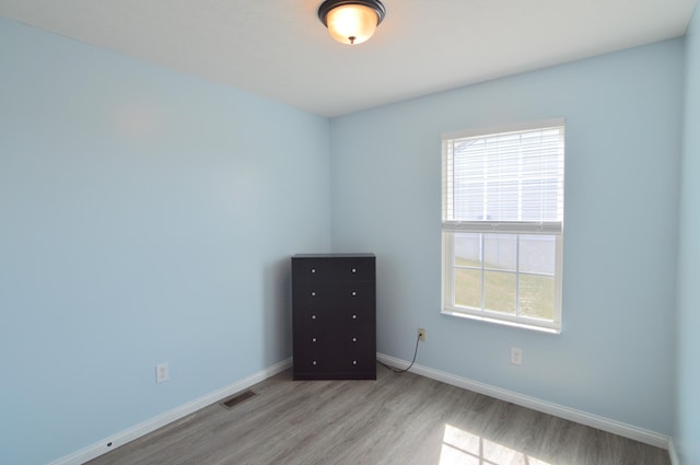 spare room featuring visible vents, wood finished floors, and baseboards