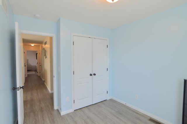 unfurnished bedroom with a closet, visible vents, light wood-style flooring, and baseboards