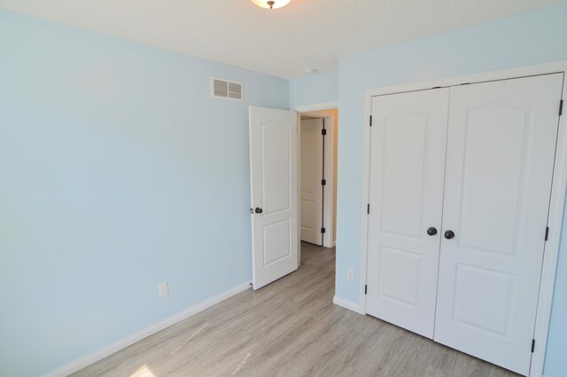 unfurnished bedroom with visible vents, baseboards, a closet, and light wood finished floors