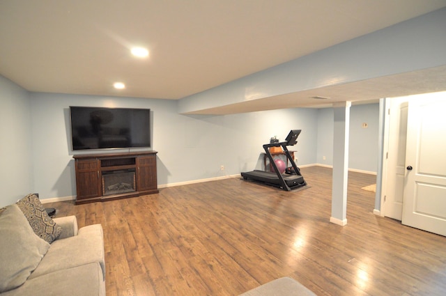 workout room featuring a glass covered fireplace, recessed lighting, wood finished floors, and baseboards