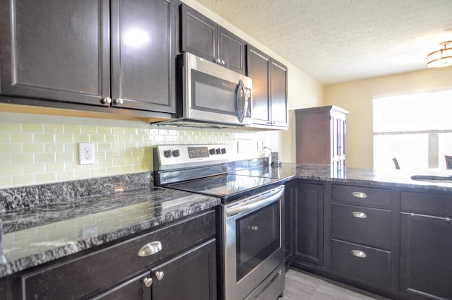 kitchen with dark stone countertops, backsplash, a textured ceiling, appliances with stainless steel finishes, and dark brown cabinets