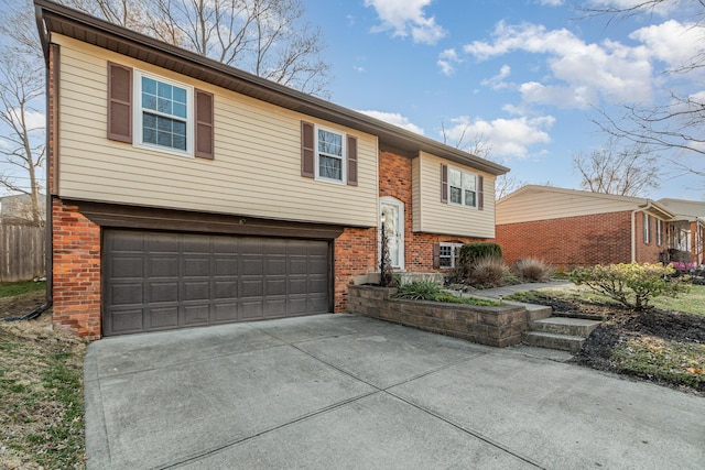 raised ranch featuring an attached garage, fence, brick siding, and driveway