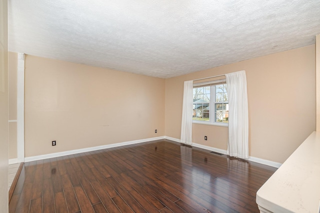 empty room featuring visible vents, a textured ceiling, dark wood-type flooring, and baseboards