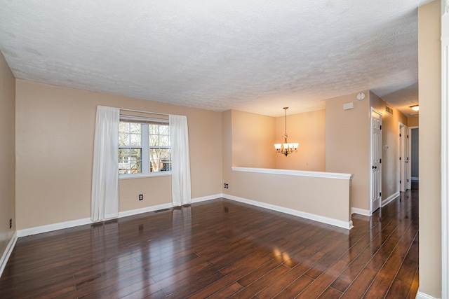 spare room featuring dark wood finished floors, visible vents, baseboards, and an inviting chandelier