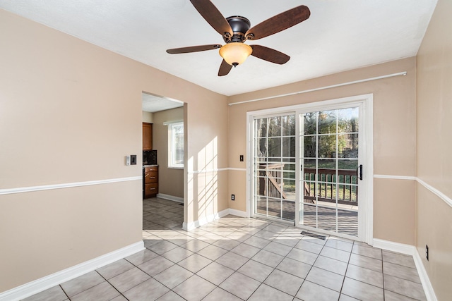 empty room featuring a wealth of natural light, light tile patterned floors, and a ceiling fan