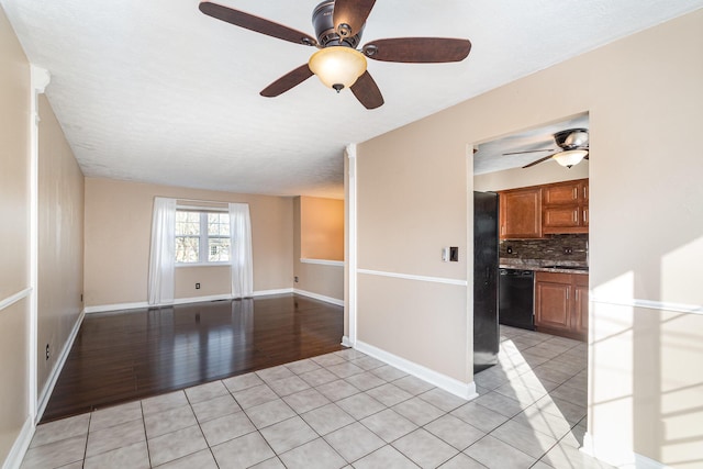 empty room featuring light tile patterned floors, baseboards, and ceiling fan