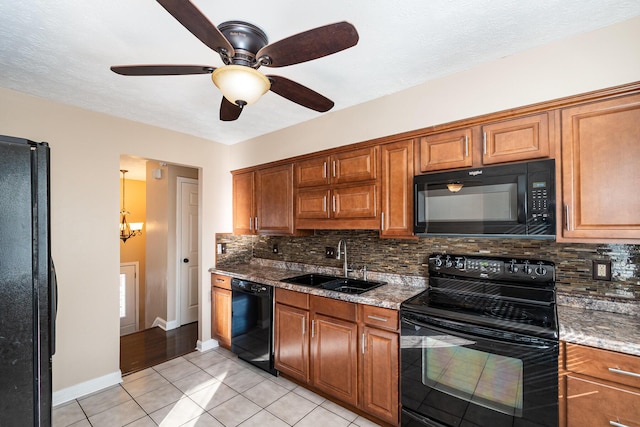 kitchen featuring decorative backsplash, brown cabinets, light tile patterned flooring, black appliances, and a sink