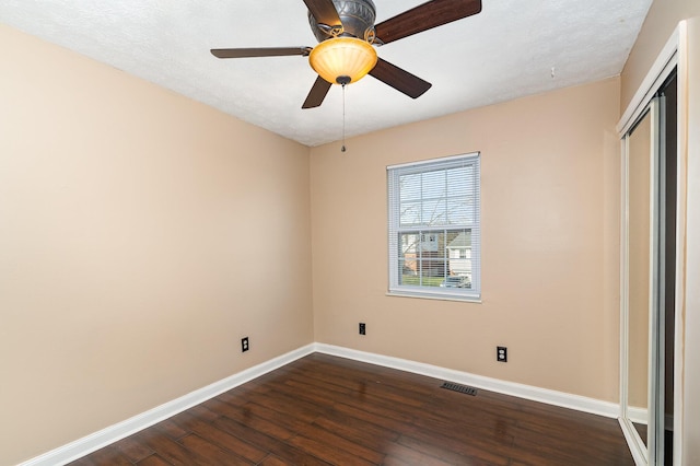 unfurnished bedroom with visible vents, ceiling fan, baseboards, a closet, and dark wood-style flooring