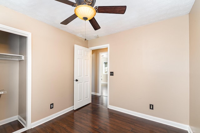 unfurnished bedroom with dark wood-style floors, baseboards, a closet, and ceiling fan