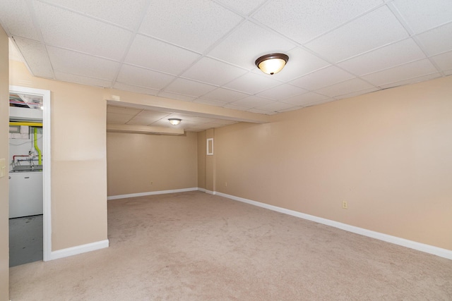 finished basement featuring carpet flooring, a paneled ceiling, and baseboards