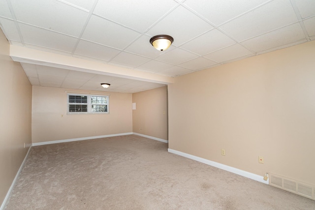 carpeted spare room with a drop ceiling, visible vents, and baseboards