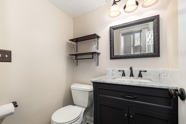 half bath with vanity, toilet, and a textured ceiling