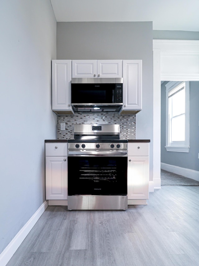 kitchen featuring decorative backsplash, appliances with stainless steel finishes, light wood-style flooring, and white cabinetry